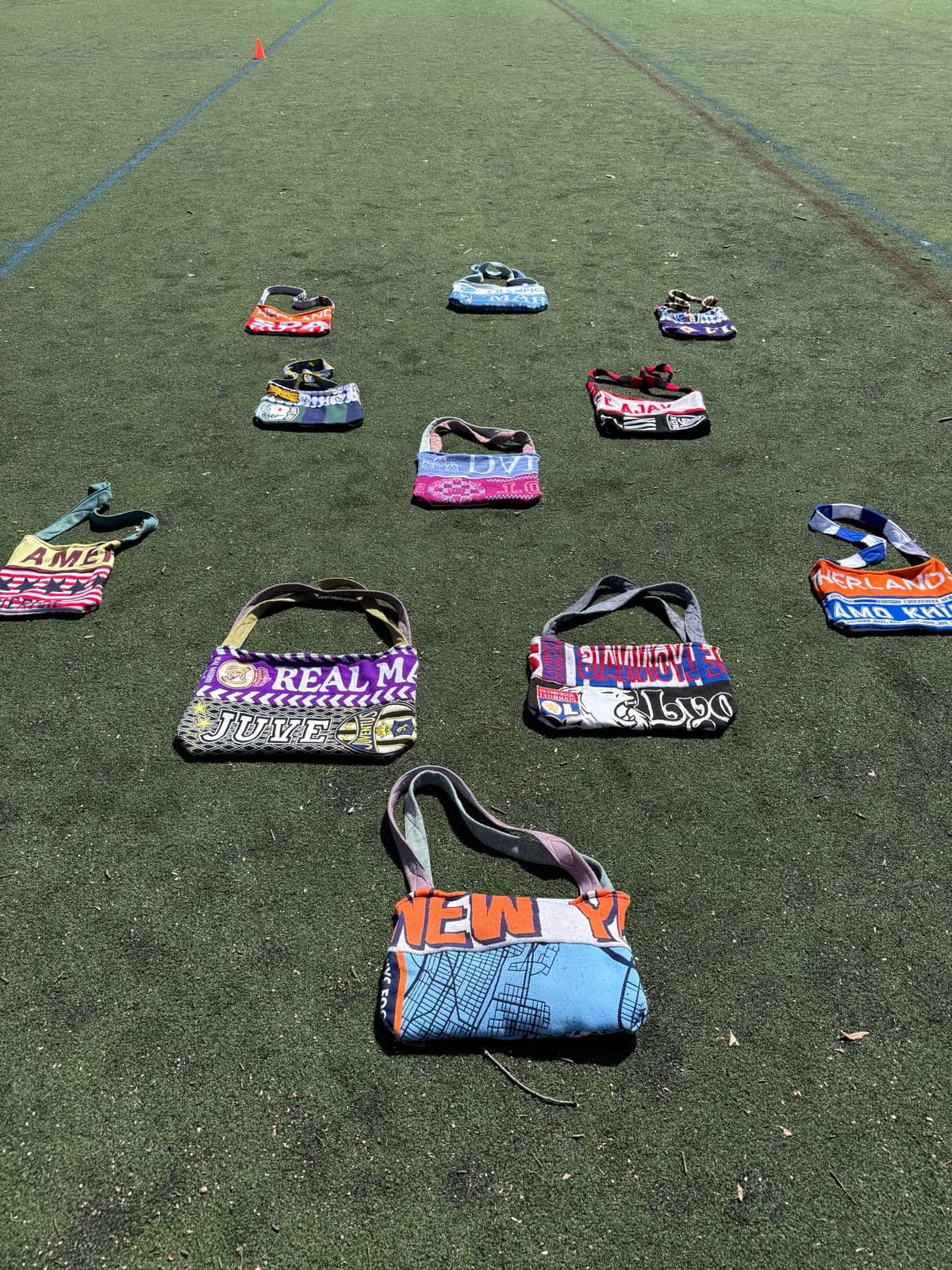 The next drop of one-of-a-kind scarf bags laid out on a football pitch